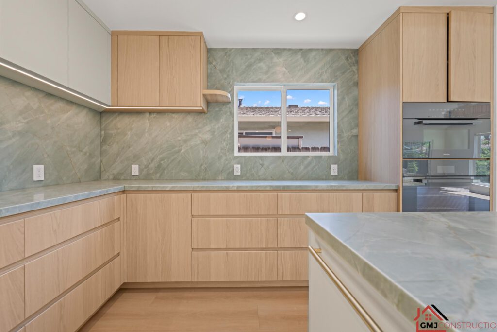 Kitchen corner with wood cabinetry, green-veined backsplash and a window