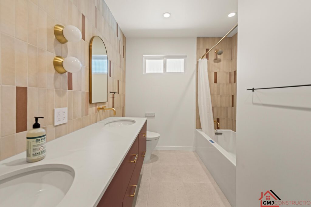 Double-vanity bathroom with arched mirrors, warm tile and a tub-shower