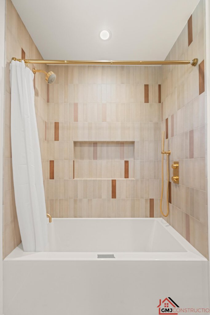 Bathtub with warm neutral wall tile and gold-toned shower hardware