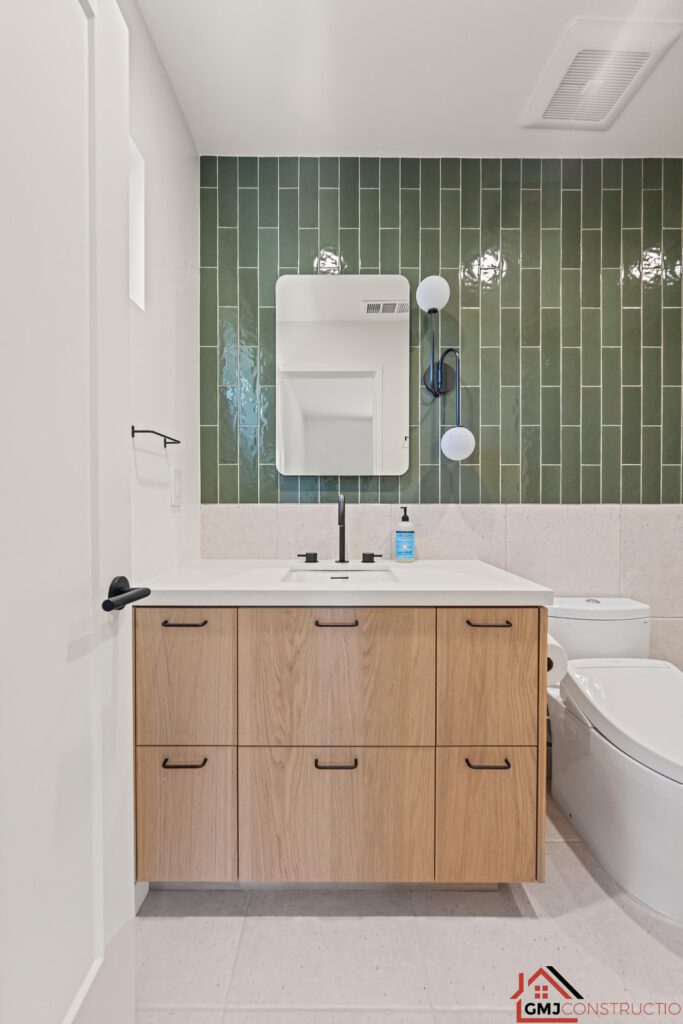 Single-sink bathroom vanity with wood drawers and a green-tiled wall