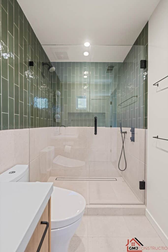 Glass-enclosed shower with green upper tile and pale lower tile at Samson Way