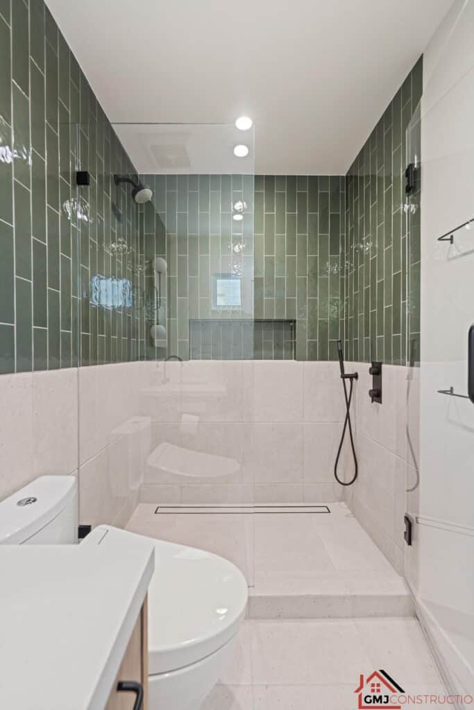 Samson Way bathroom with green wall tile, a glass shower enclosure and dark fixtures