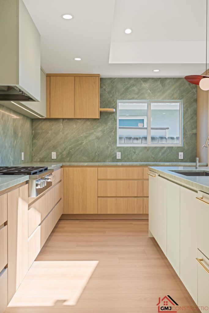 Wood kitchen cabinets and green-veined surfaces beside the island at Samson Way