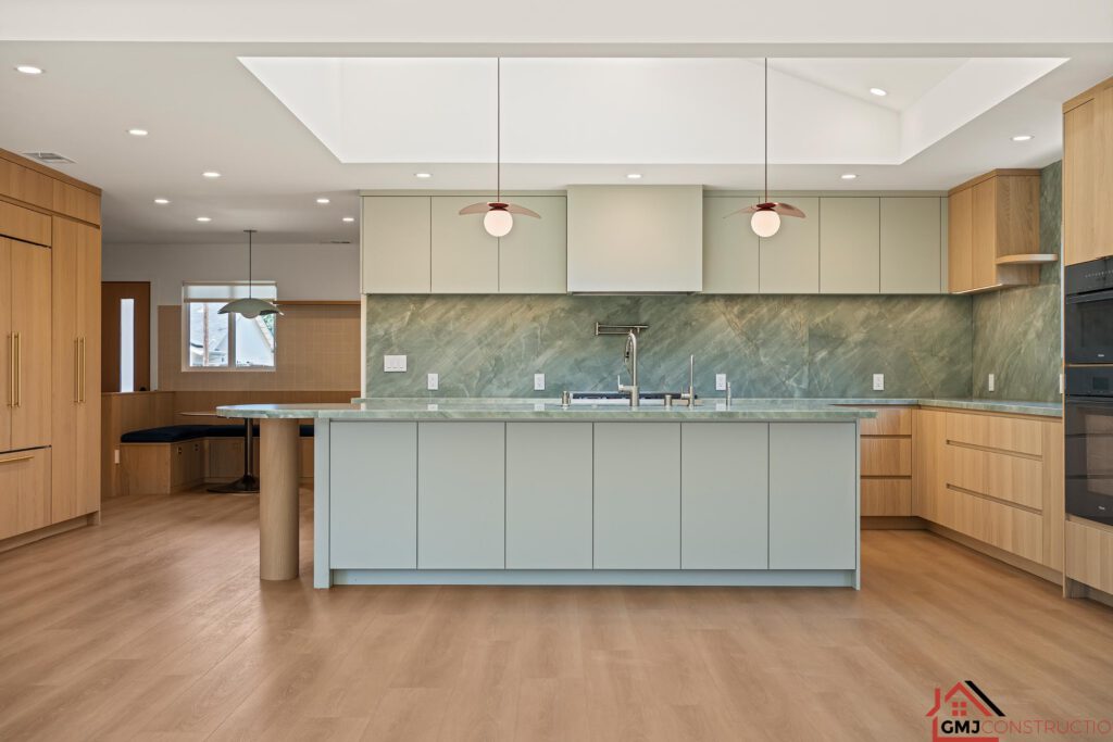 Front view of the kitchen island with pale cabinetry and red-toned pendant lights