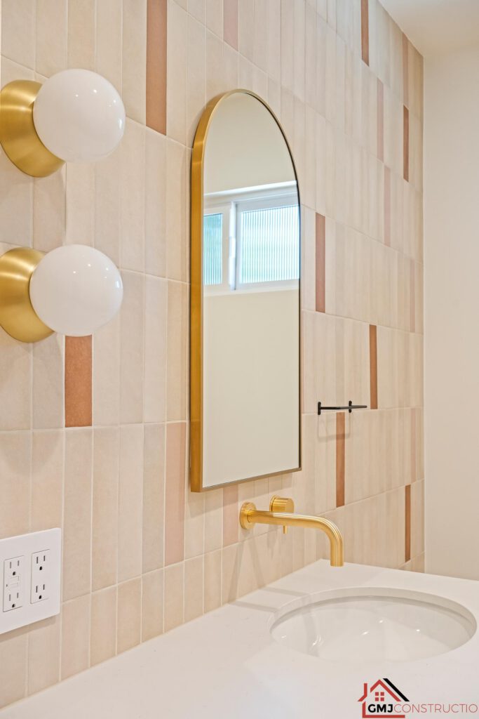 Arched bathroom mirror, globe sconces and gold-toned wall-mounted faucet