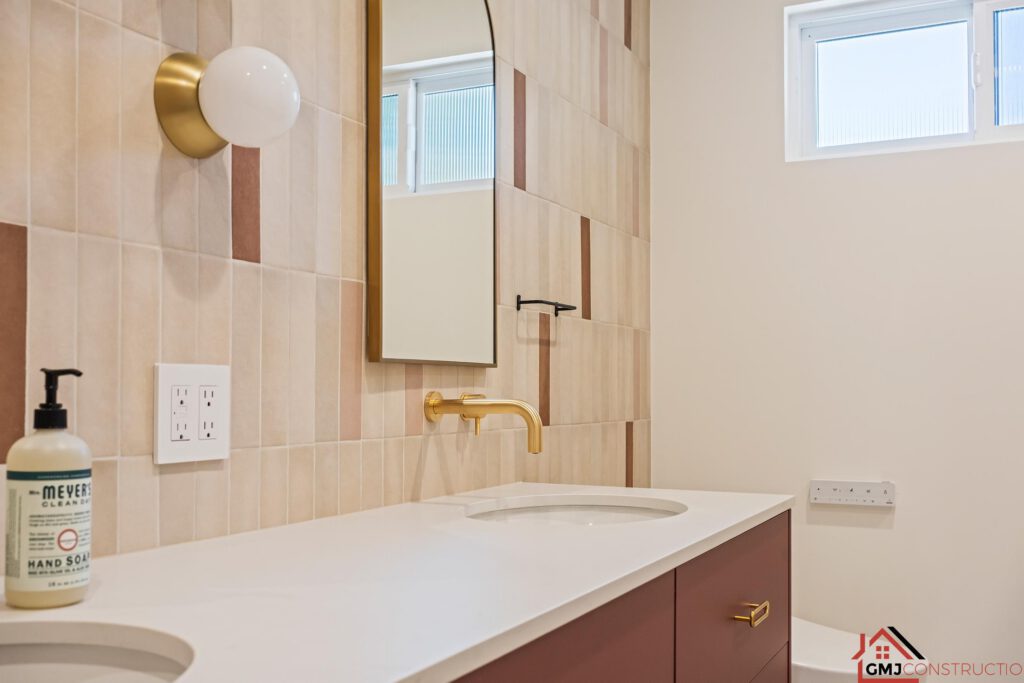 Double-vanity bathroom sink and warm-toned tile near the window