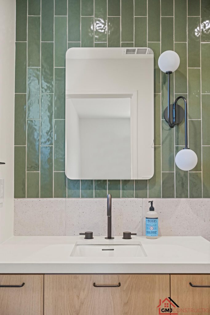 Bathroom mirror and globe sconces above a white sink and wood vanity