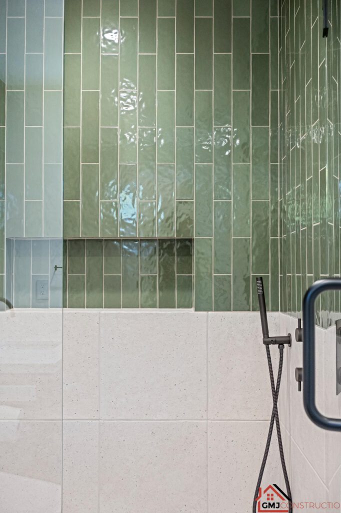 Green shower tile, recessed niche and dark handheld shower fixture