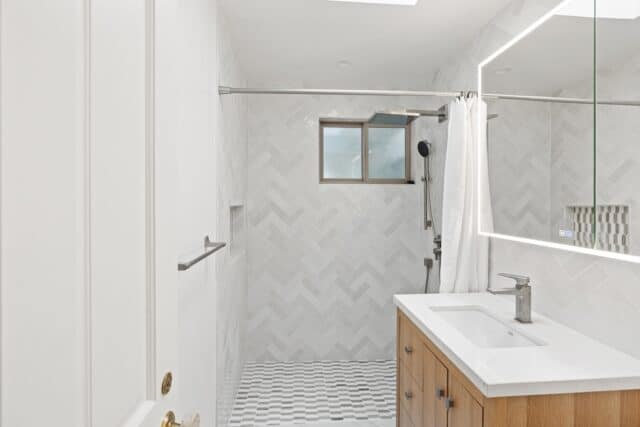 Carlson Cir bathroom in Palo Alto with a wood vanity, illuminated mirror and white tiled shower